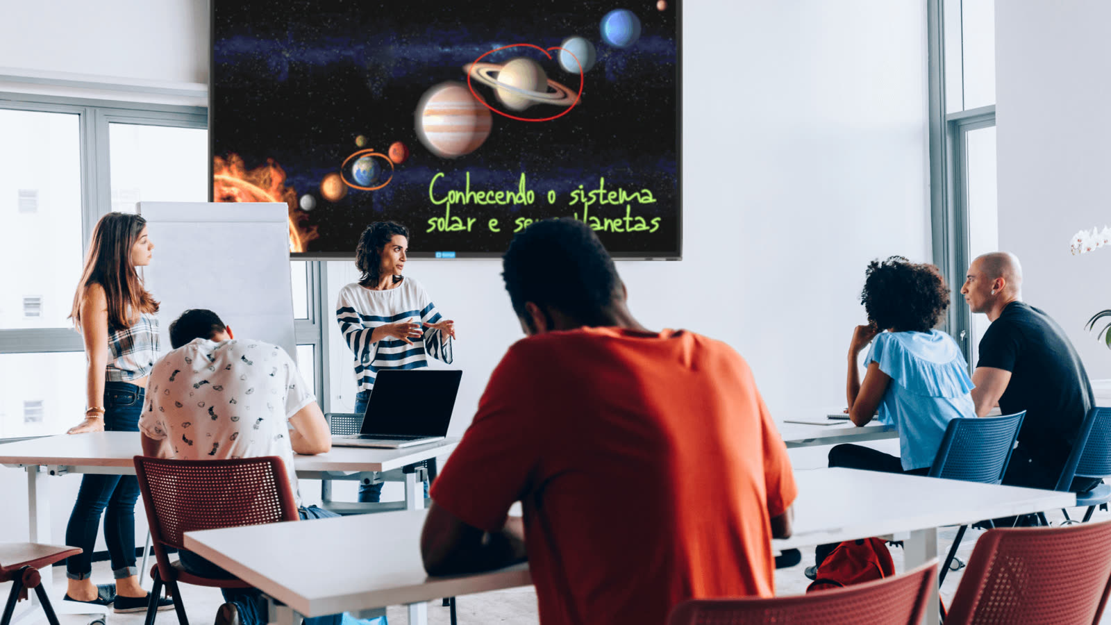 Sala de aula com alunos assistindo a uma explicação do professor